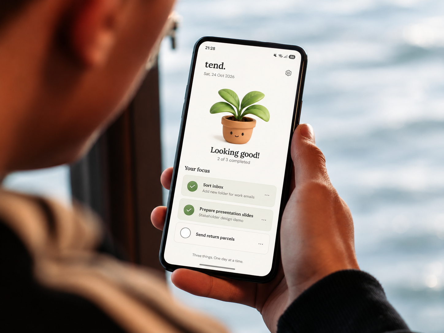 Window-side handheld phone mockup showing tend.’s plant and three daily priorities